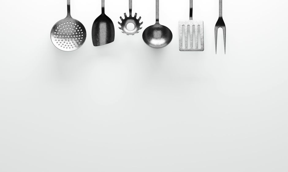 Hanging kitchen utensils against a clean white background, perfect for cooking themes.