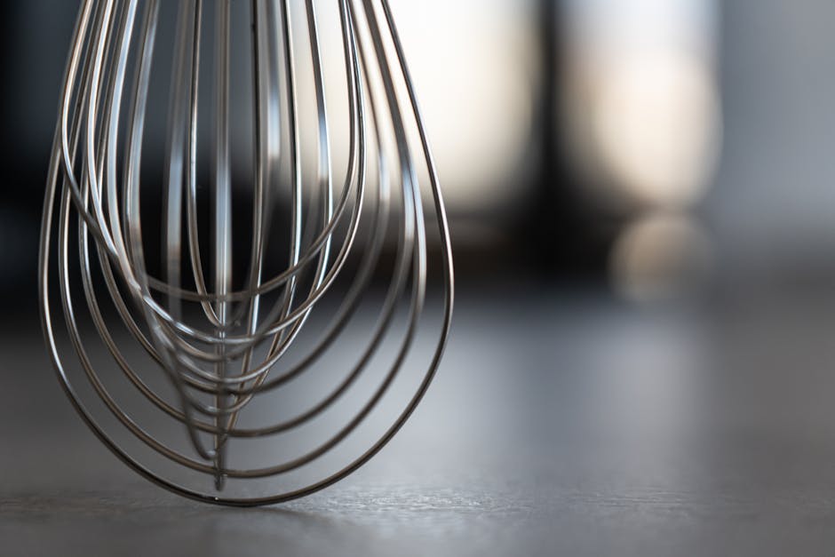 Close-up of a stainless steel whisk in a modern kitchen setting, showcasing sleek design.