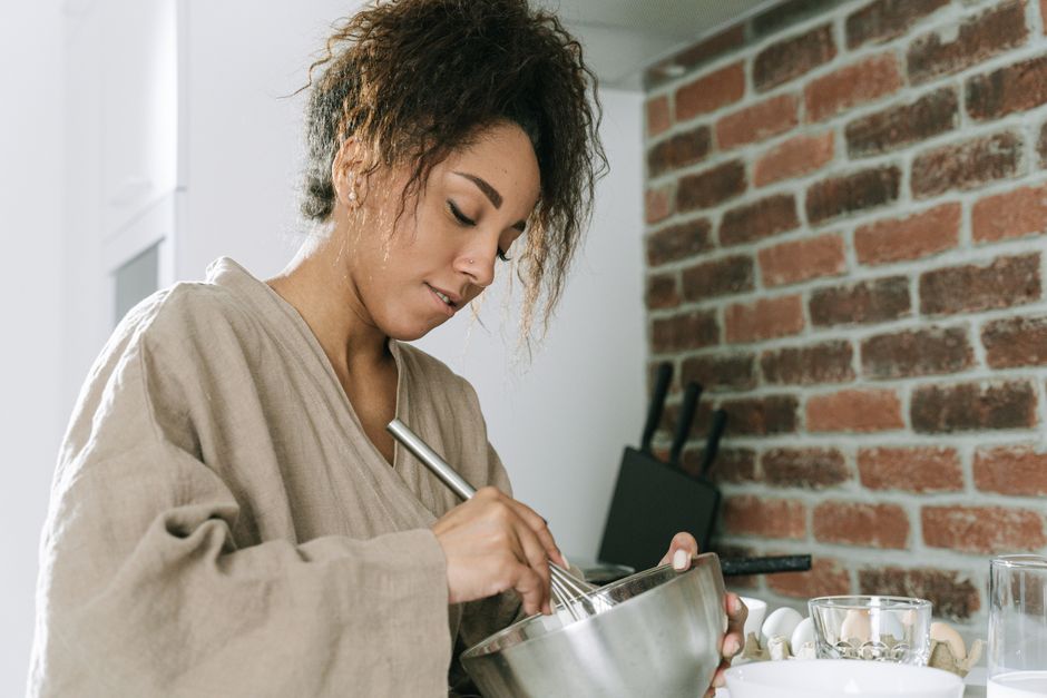 Young woman preparing food in a modern kitchen, mixing ingredients with focus.